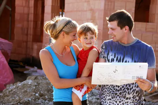 Fotolia_9609177_Subscription_XXL_01 Junge Familie mit einem Kind vor Rohbau.